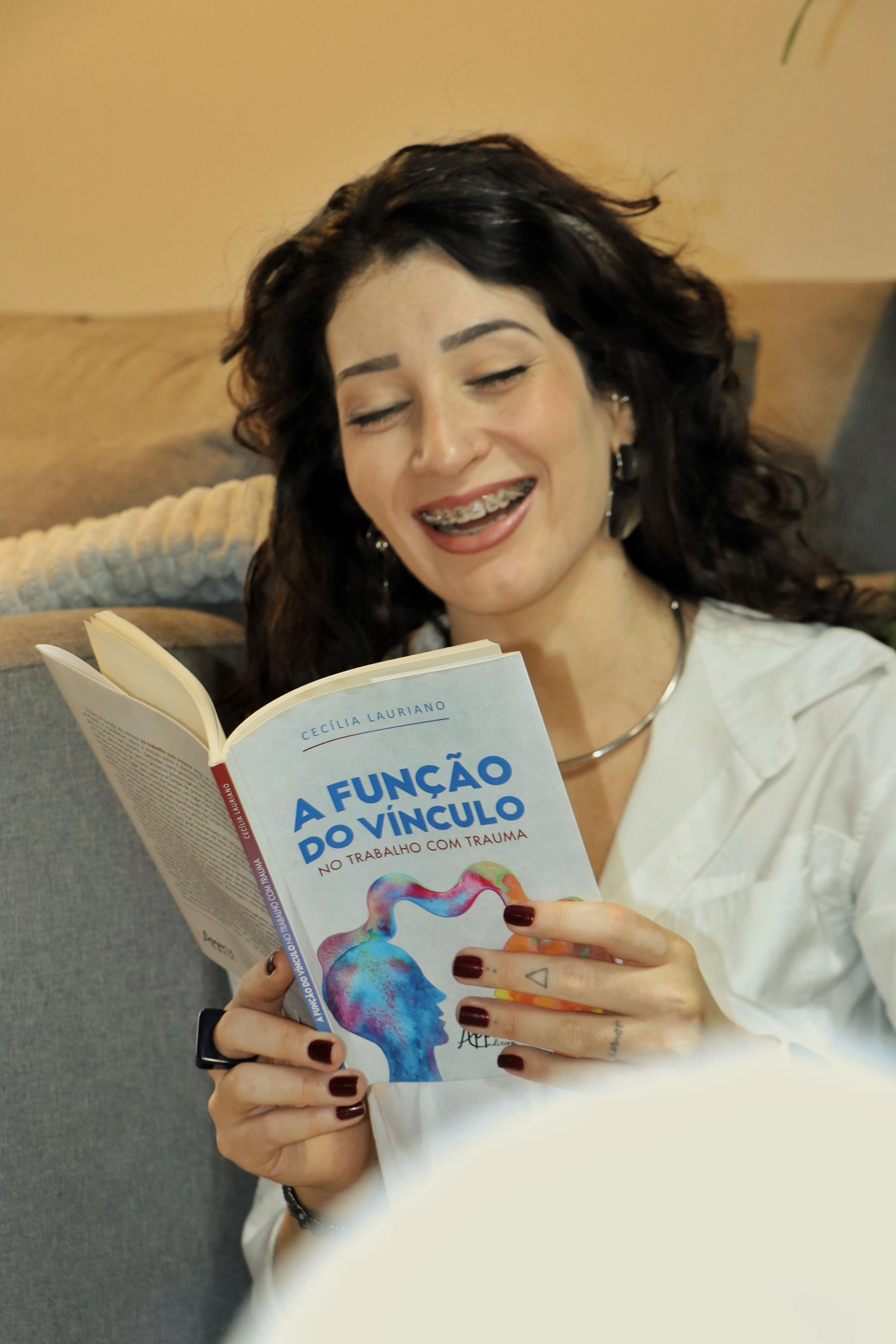 Tallyesle Almeida, psicóloga, sorrindo enquanto segura um livro